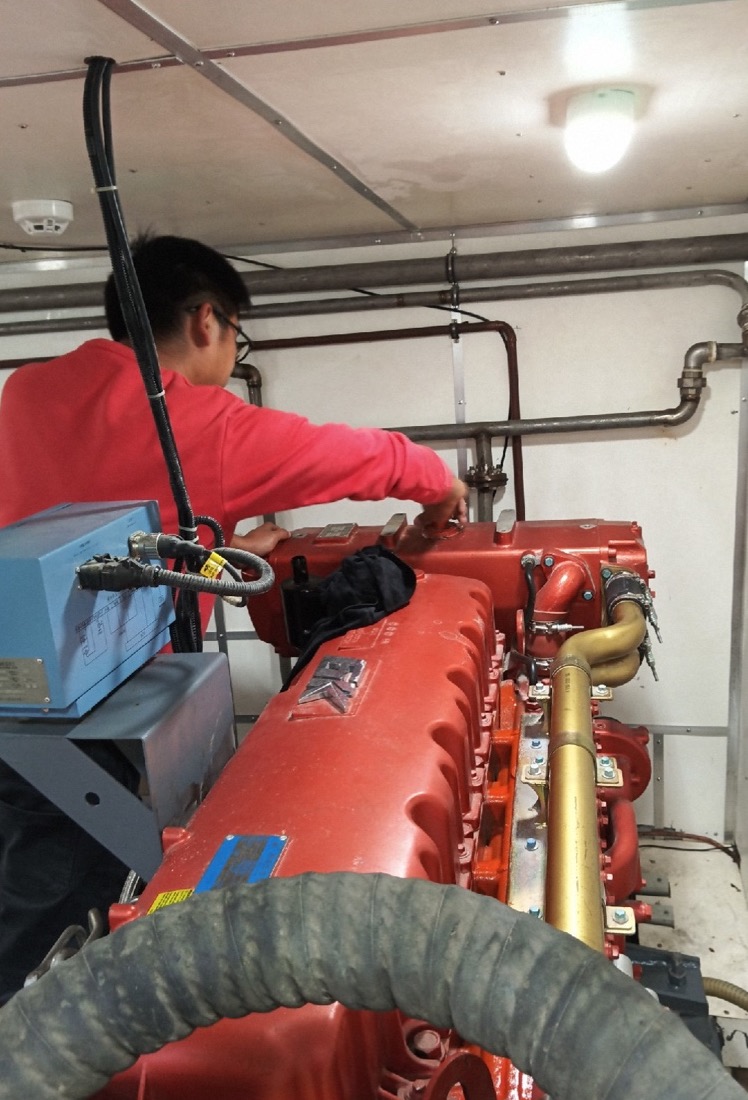 Technician repairing an engine in the engine room