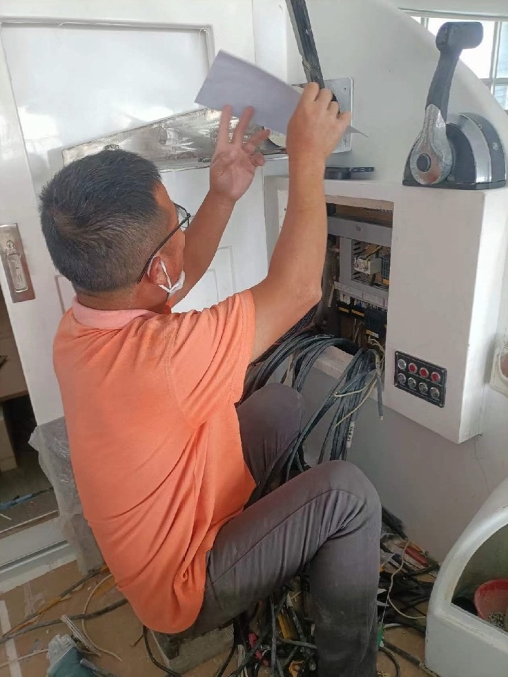 Technician working on electrical wiring in a yacht console